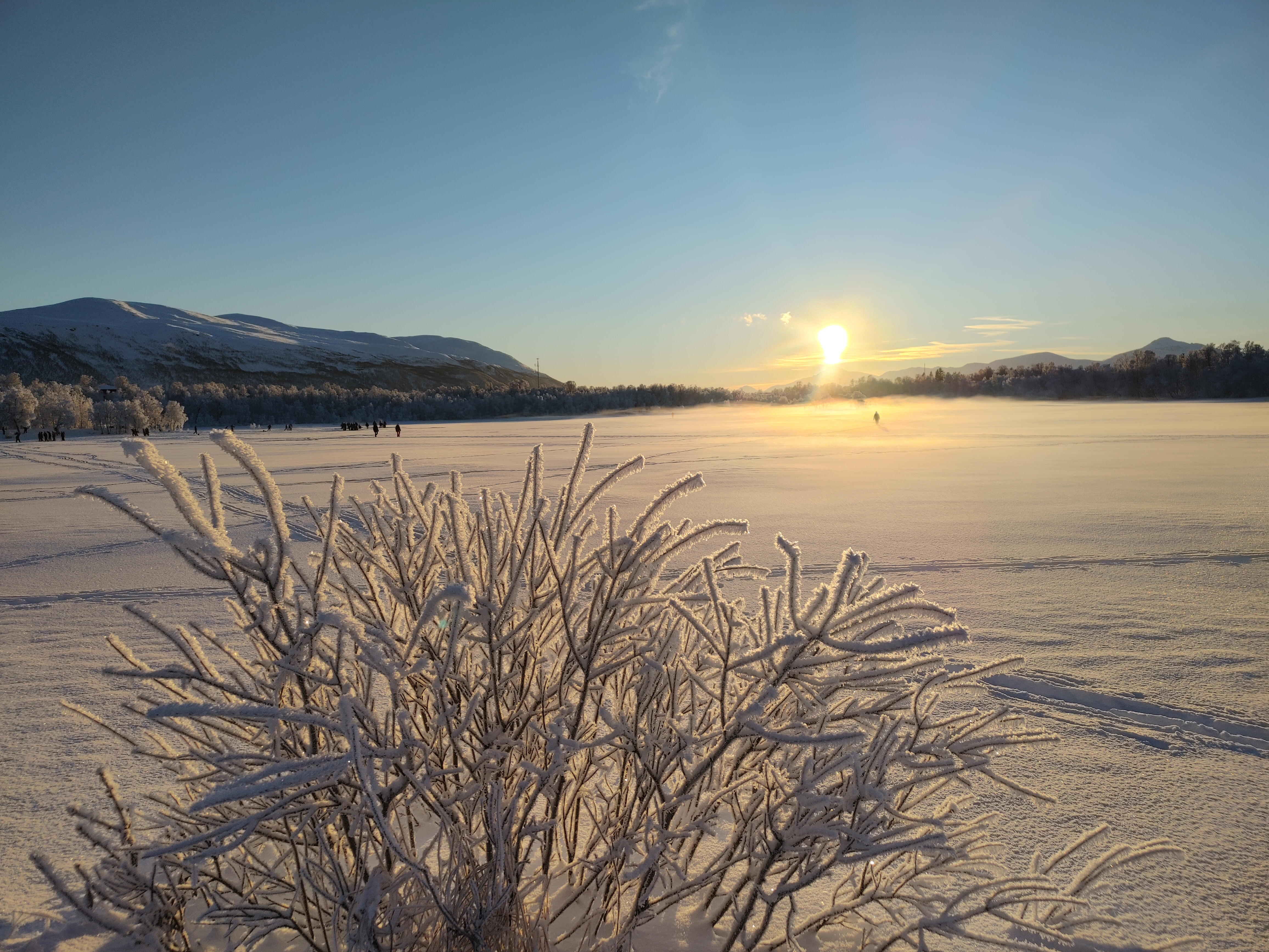 Winter in Tromso, Norway. Photo taken in Prestvannet with the view of the mountains, snow, and the sun just starting to emerge after the polar night period. 